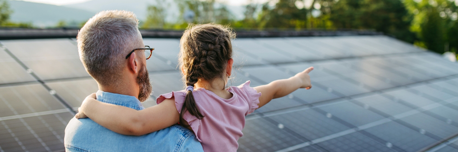 Father and daughter admiring solar panels on residential rooftop with mountain view, professional solar installation services for homes and businesses