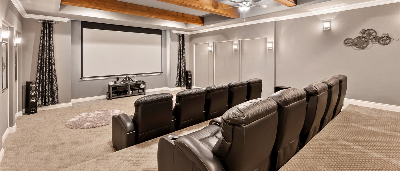 Traditional home theater featuring leather recliners, projection screen, exposed wood beams, wall sconces and audio equipment for comfortable movie viewing