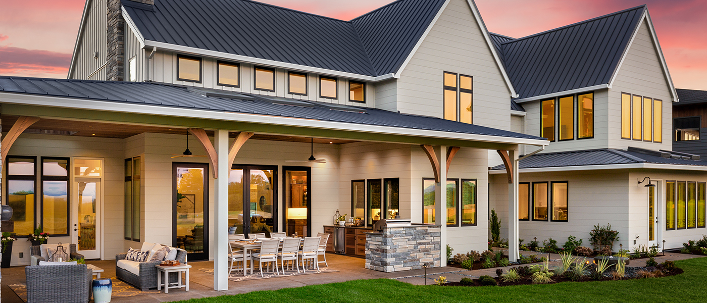 Modern two-story home with warm interior lighting and Generac backup generator installed at dusk, showcasing residential power protection